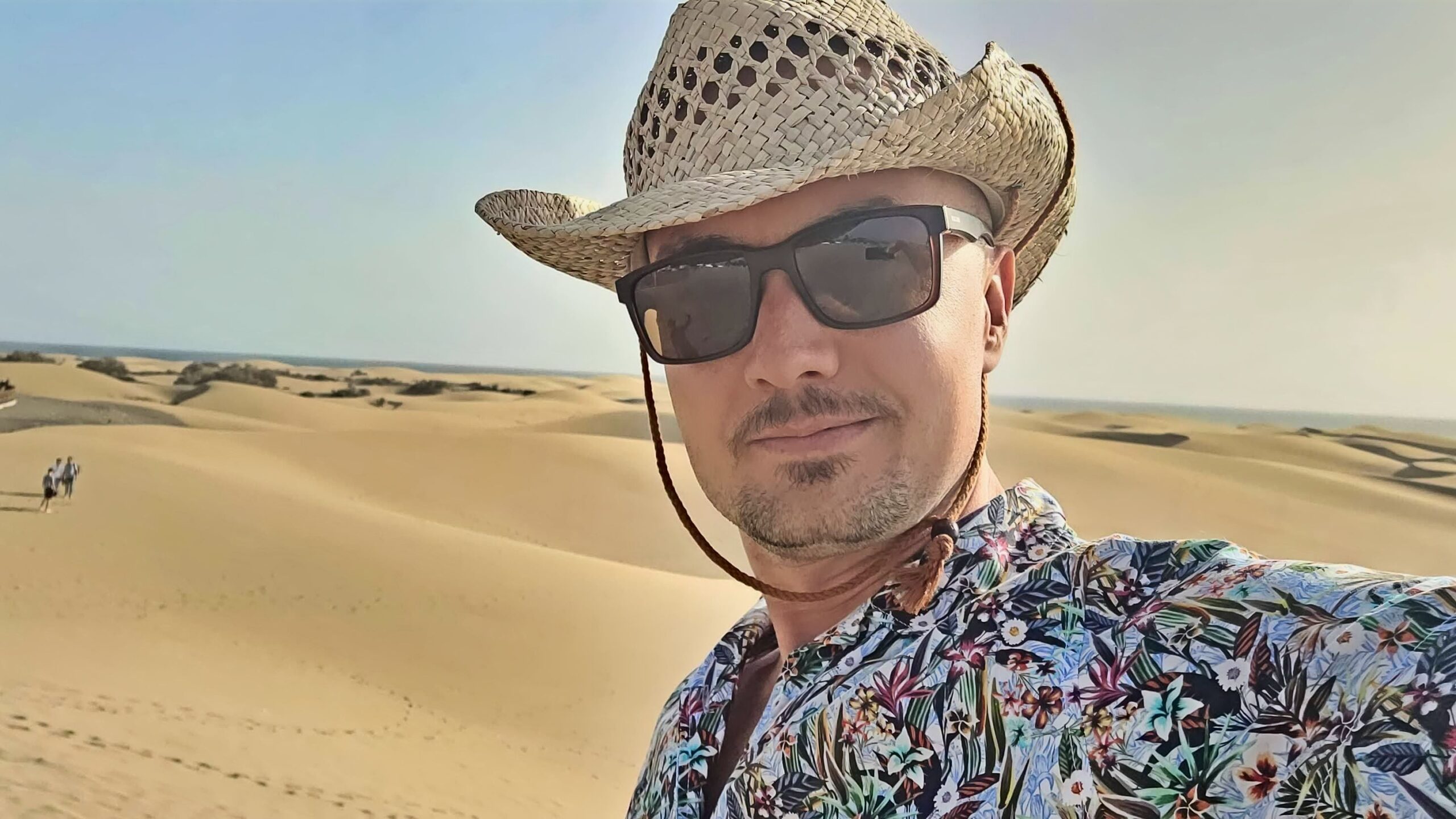 Tomasz Micherda w kapeluszu na tle piaszczystych wydm